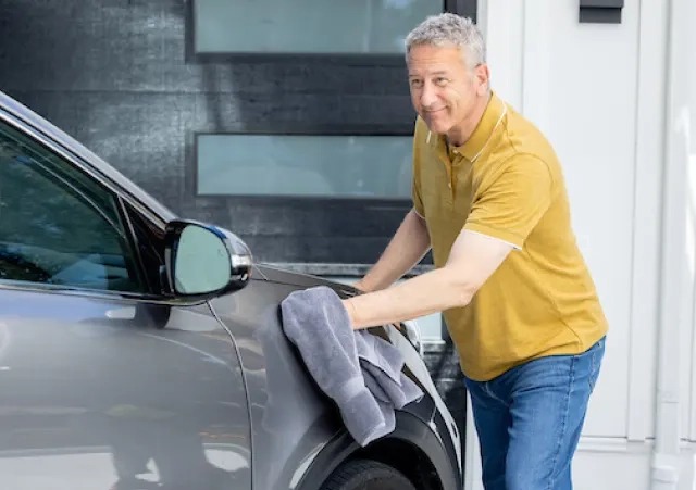 man in yellow shirt drying his car with a towel