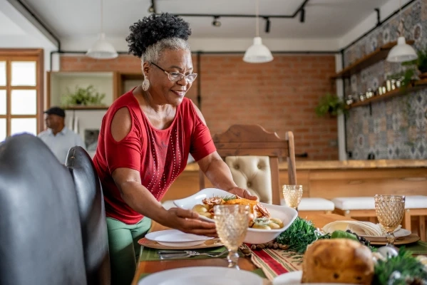 woman in red shirt placing plate of food on table